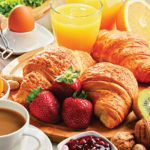 Breakfast consisting of croissants, coffee, fruits, orange juice, coffee and jam. Balanced diet.