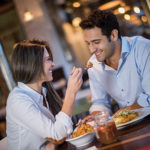 Loving couple in a romantic dinner at a restaurant and woman feeding her boyfriend