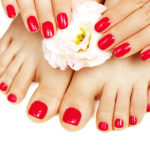 Red manicure and pedicure with flower close up, isolated on white background